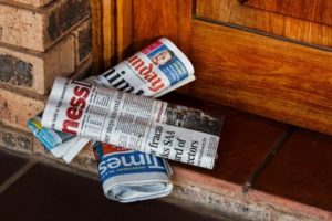 daily paper piled on doorstep